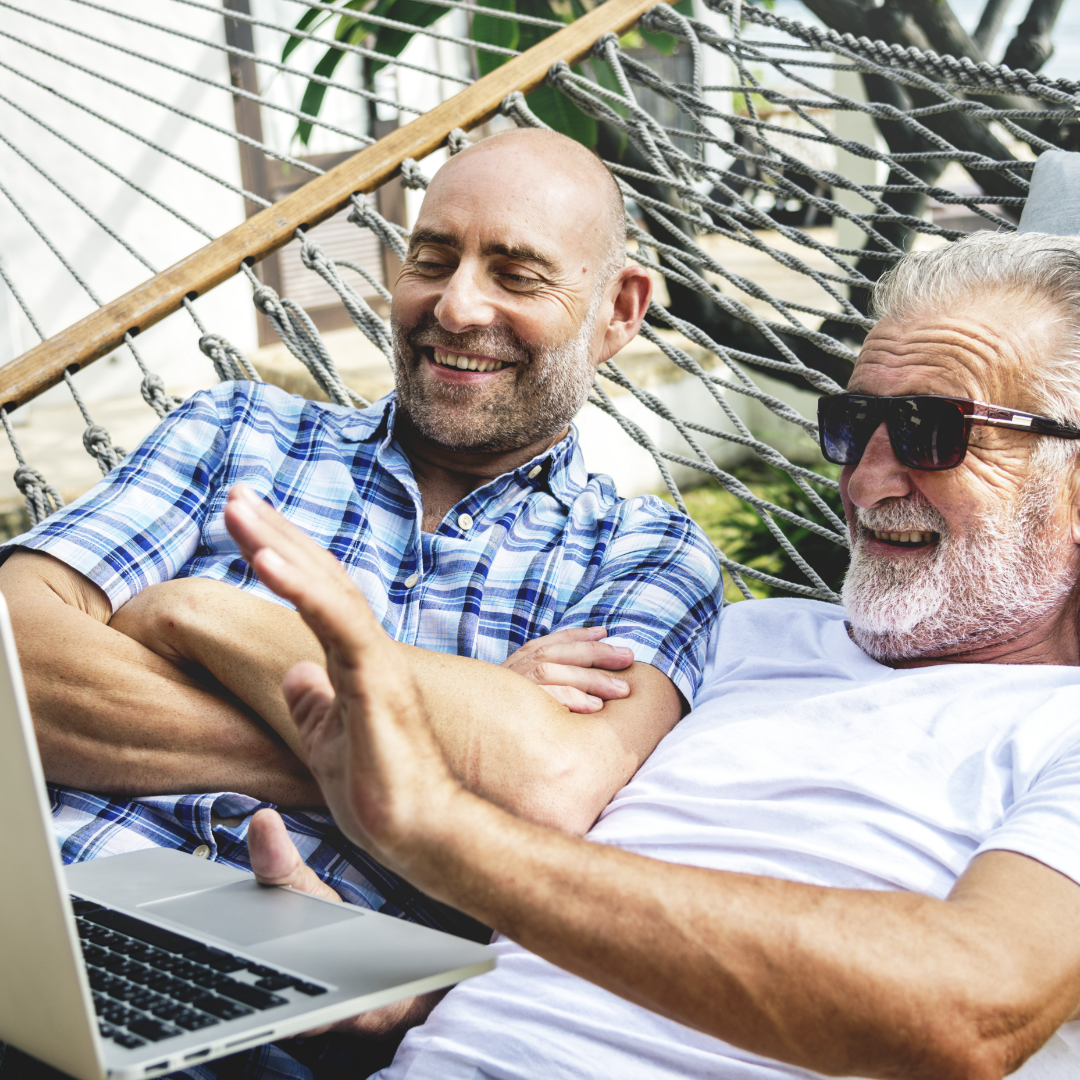 Two men looking at computer in hammock – 1